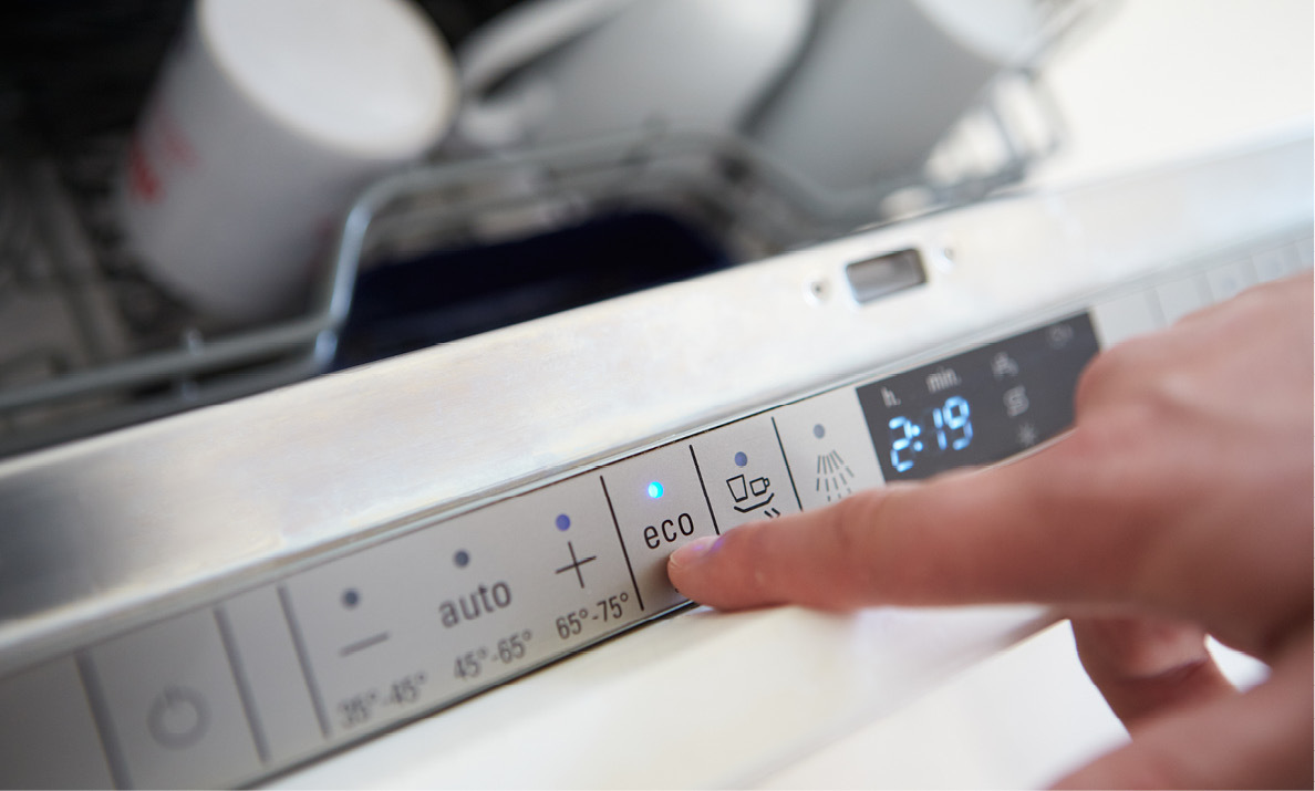 person pressing eco button on dishwasher
